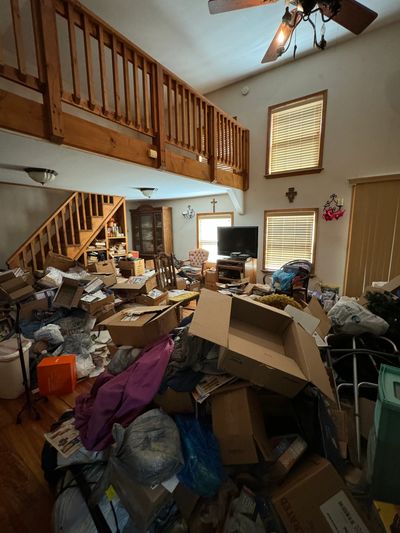 Hoarding living room before clean all covered in boxes and trash