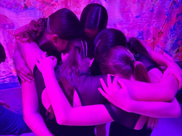 Group hug under purple lighting shows close bond and support.