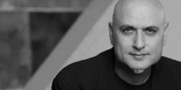 Black and white portrait of a bald man wearing a dark jacket.