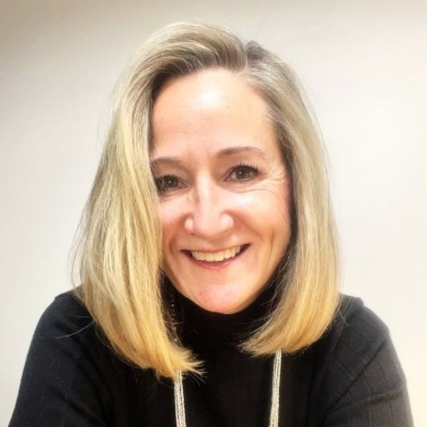 Smiling woman with blonde hair wearing a black top.