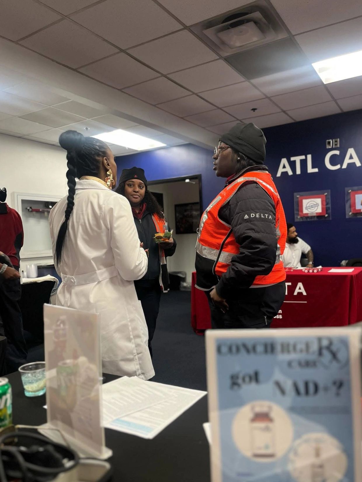 Three women in conversation, two wearing Delta uniforms with safety vests.