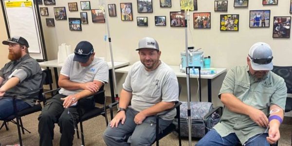 Four men donating blood while sitting in a medical room.