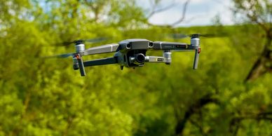 A DJI Mavic 2 drone flying outdoors with trees in the background.