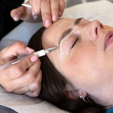 Eyebrow shaping with white pencil markings on a woman's face.