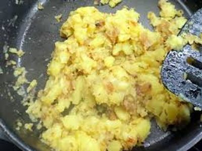 Scrambled eggs cooking in a pan with a spatula.