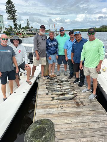 Group of men on a dock displaying their freshly caught fish.