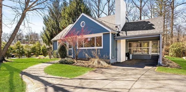Blue house with a curved driveway and a well-maintained lawn.