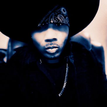 Person wearing a large black hat and bandana, with a chain necklace.