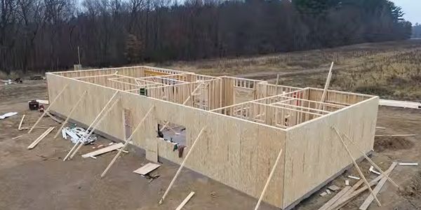 Wooden frame and panel walls under construction on a building site.