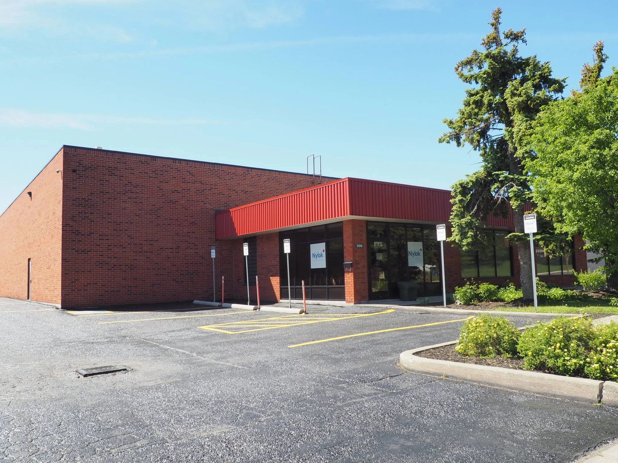 A brick commercial building with a red awning and parking spaces in front.