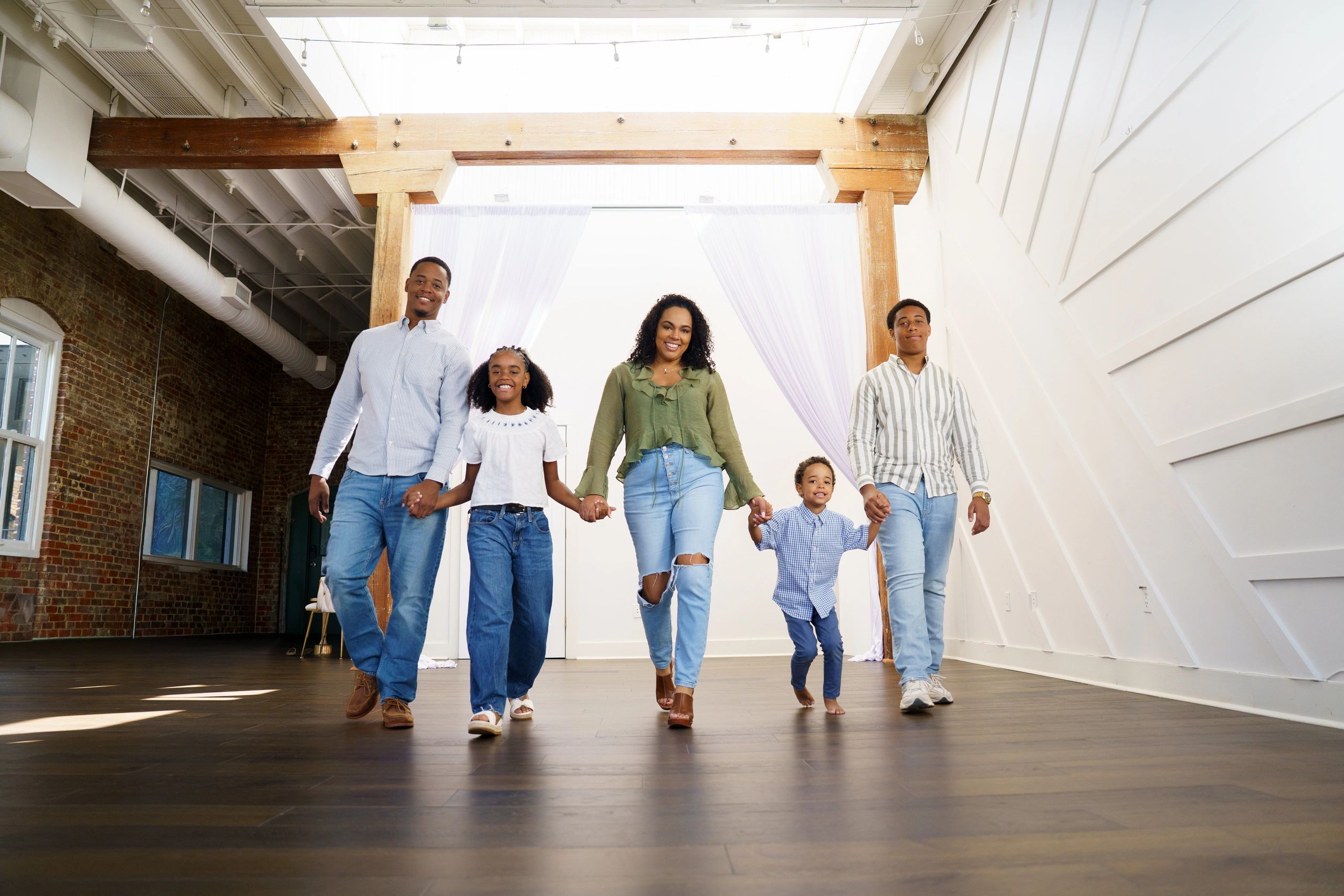 Happy family holding hands and walking indoors.