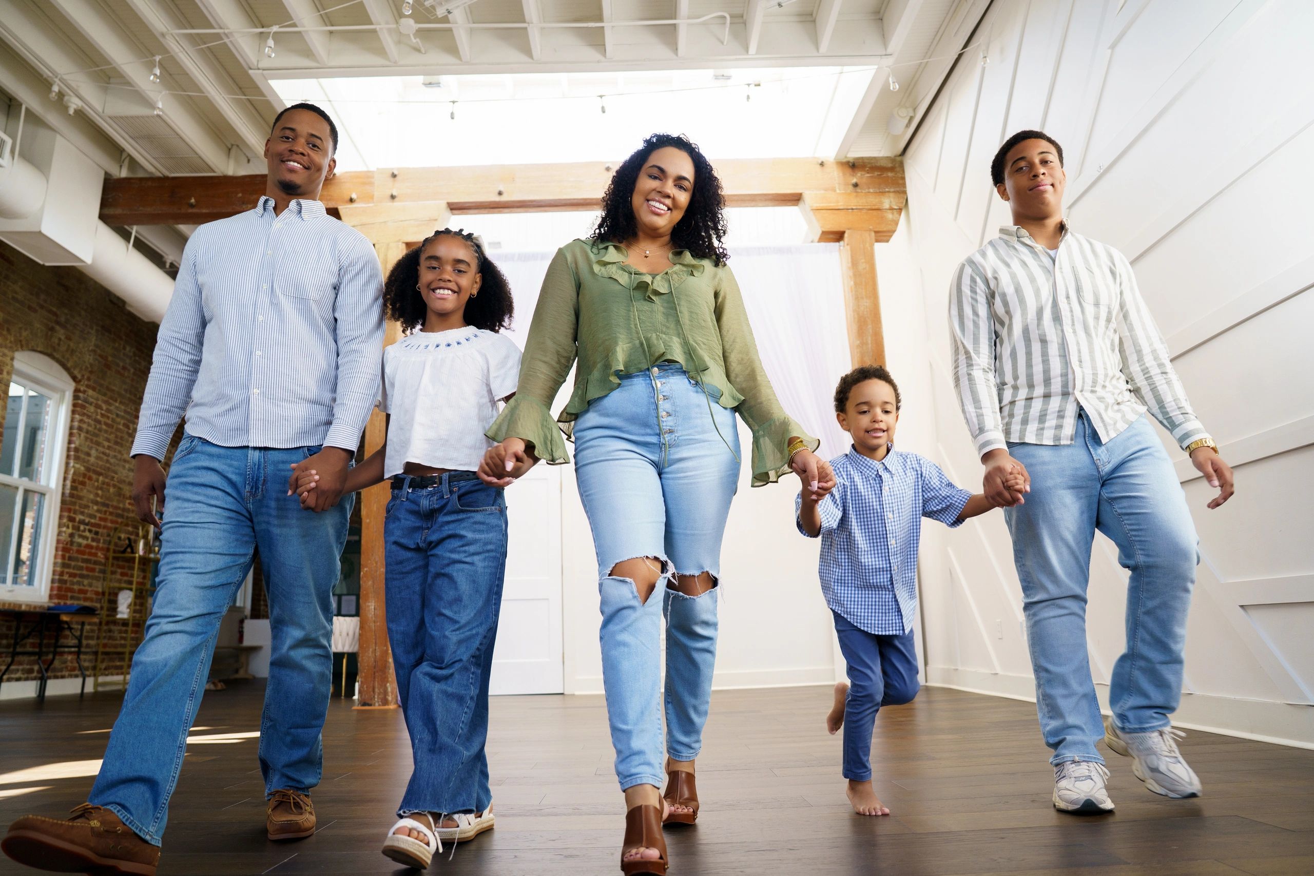 A happy family holding hands and walking indoors.