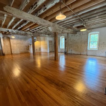 Empty room with wooden floors and exposed beams.