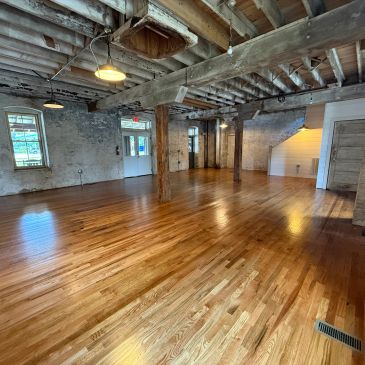 Empty rustic room with wooden floor and exposed beams.