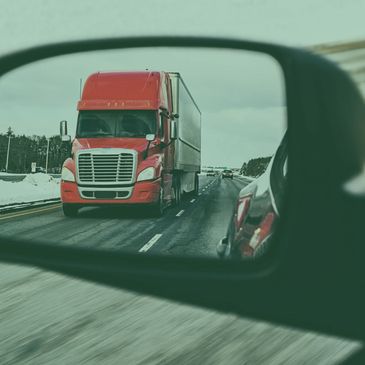 Big rig in rear view mirror transporting across the nation on the interstate