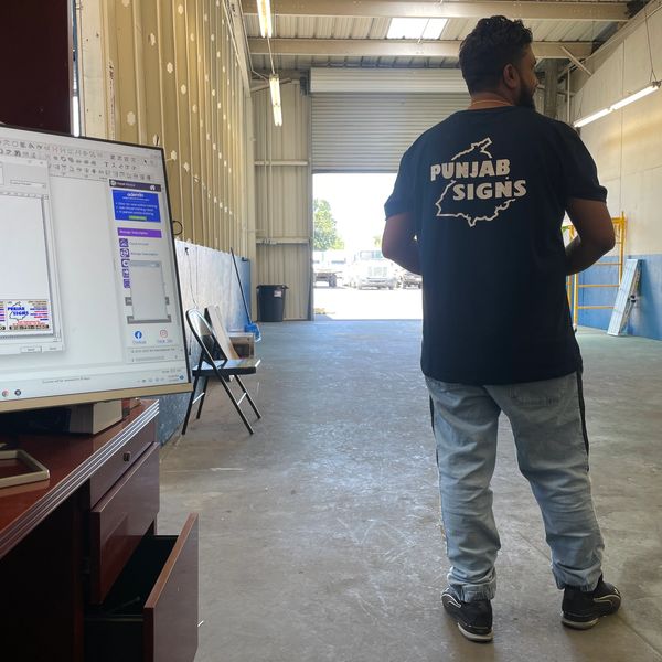Man wearing a Punjab Signs t-shirt stands inside a large warehouse space.