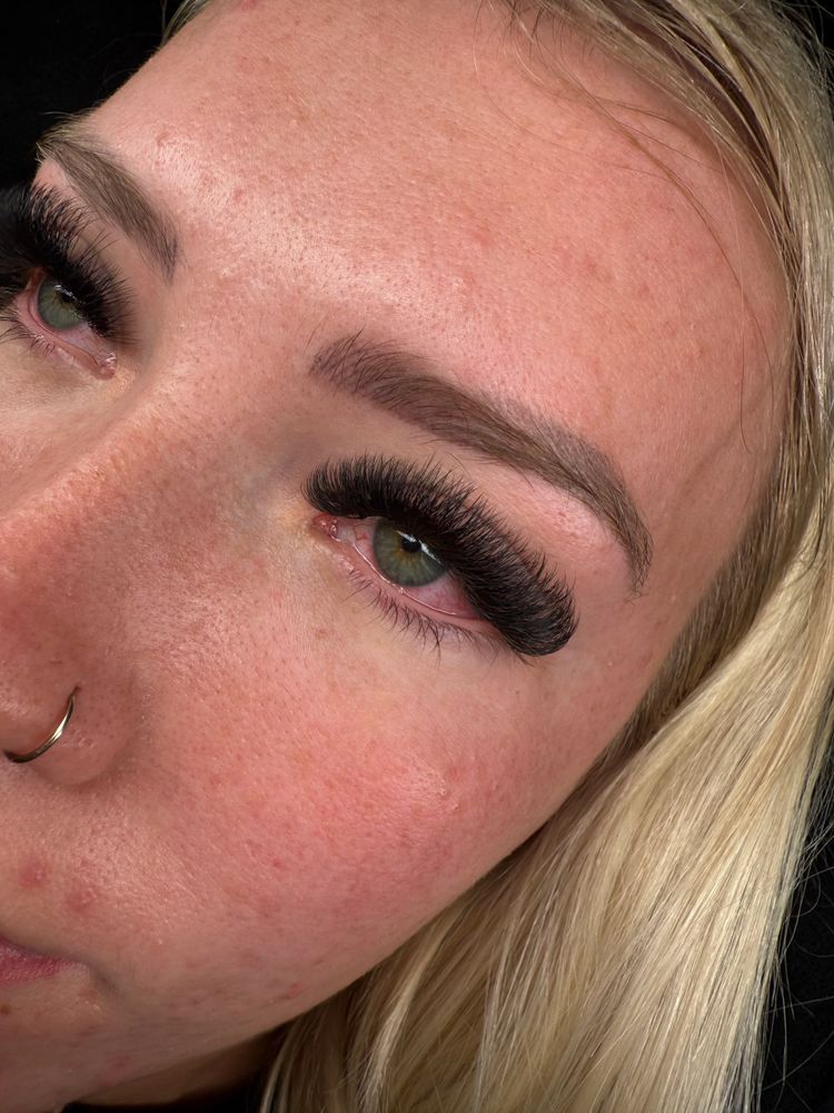 Close-up of a woman's eye with long false eyelashes and a nose ring.
