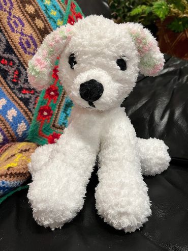 crocheted fuzzy white puppy with rainbow ears.