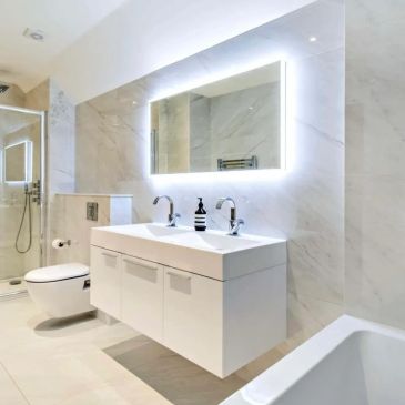 Modern white bathroom with double sinks and illuminated mirror.