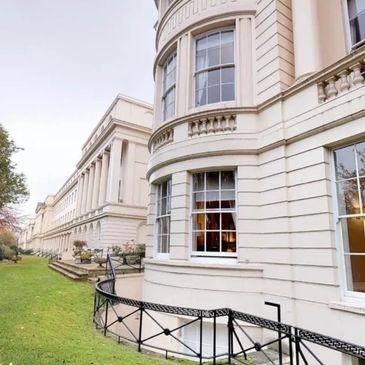 Large historic building with curved facade and green lawn.