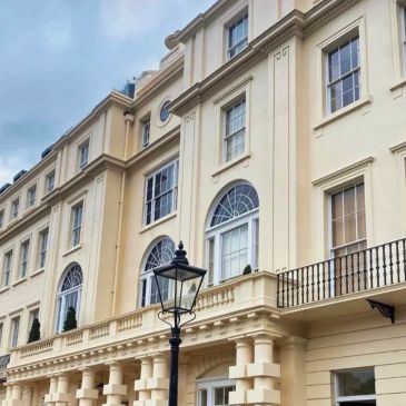Elegant beige building with arched windows and lamppost.