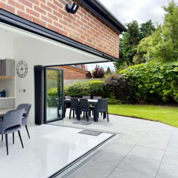 Modern open patio with outdoor dining set and greenery.