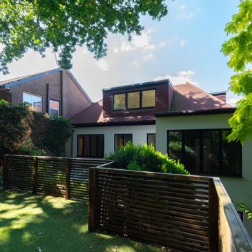Modern house with large windows and wooden fencing.