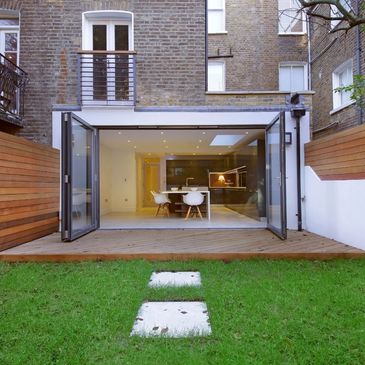 Modern house with open glass doors leading to a garden.