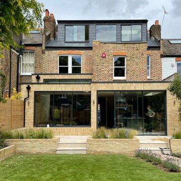 Modern extension on a traditional brick house with large glass doors.