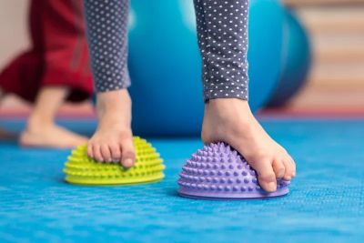 Child exercising toes on spiky balance pods.