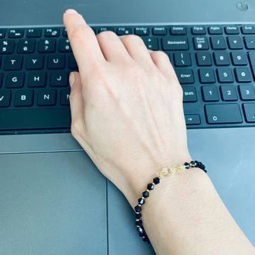 A person's hand wearing a black and yellow bracelet.