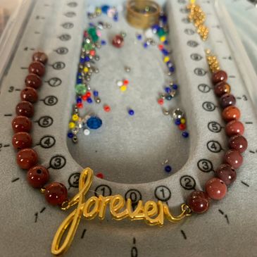 Beads laid out on a beading board to create a necklace.