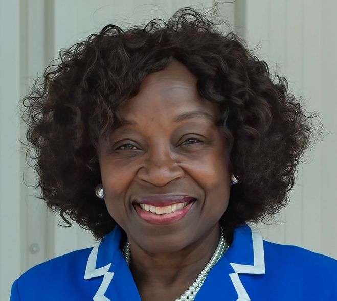 Smiling woman with curly hair in a blue jacket.