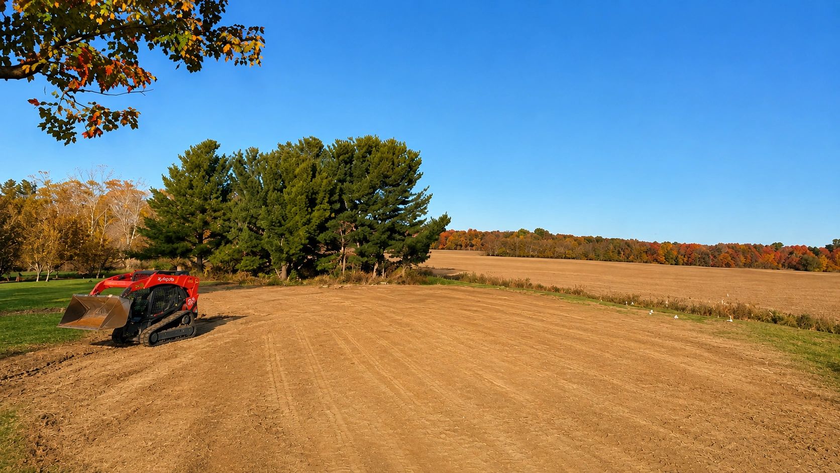 Red skid steer on freshly plowed field in autumn.