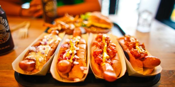 Four hot dogs with various toppings on a tray at a restaurant.
