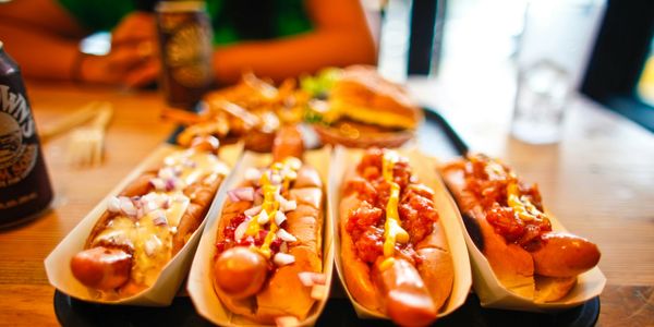 Four hot dogs with various toppings on a tray at a restaurant.
