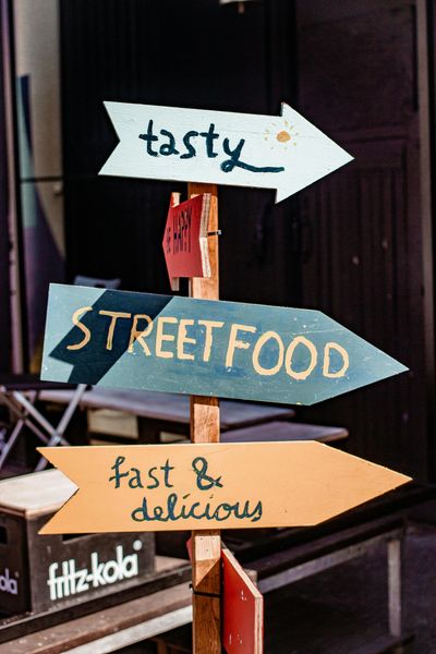 Colorful wooden signs pointing to tasty street food and fast, delicious meals.