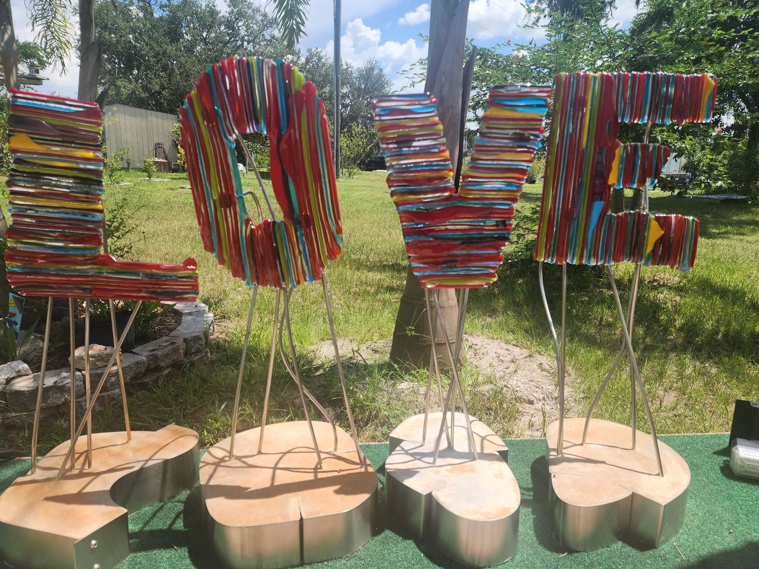 Colorful striped letters spelling LOVE on stands outdoors.