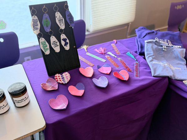 Handcrafted keychains, heart-shaped crafts, and bookmarks on a purple tablecloth.