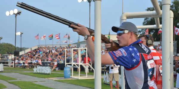 Shooter aiming a shotgun at a sports event.