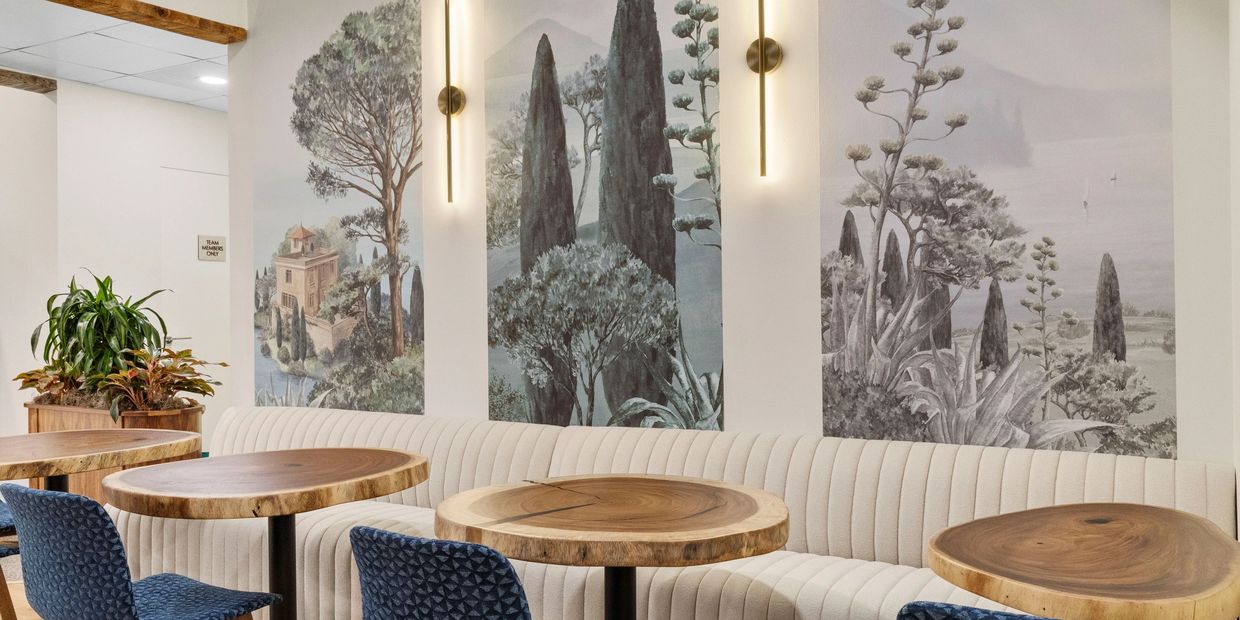 Elegant seating area with wooden tables, blue chairs, and a scenic mural on the wall.