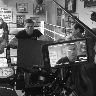 Filming an interview in a boxing gym with a focus on a boxer inside the ring.