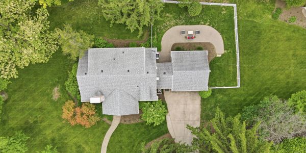 Aerial view of a house with a fenced backyard and green lawn.