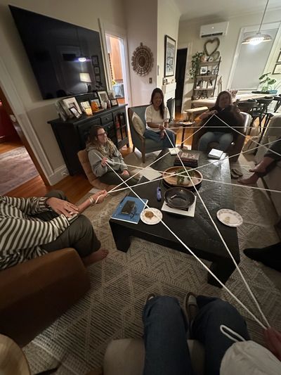 Friends playing a social game with string in a cozy living room.