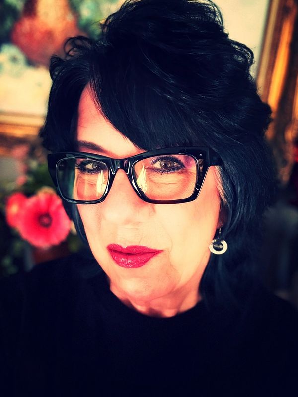 Close-up portrait of a woman wearing glasses with bold lipstick.