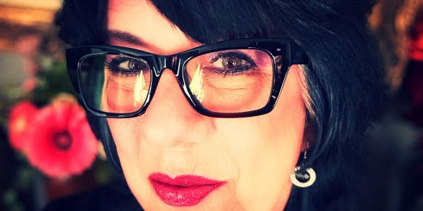 Close-up portrait of a woman wearing glasses with bold lipstick.