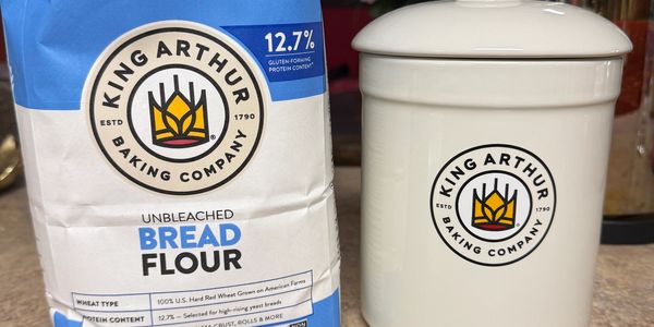 King Arthur Baking Company's unbleached bread flour bag next to a matching flour container.