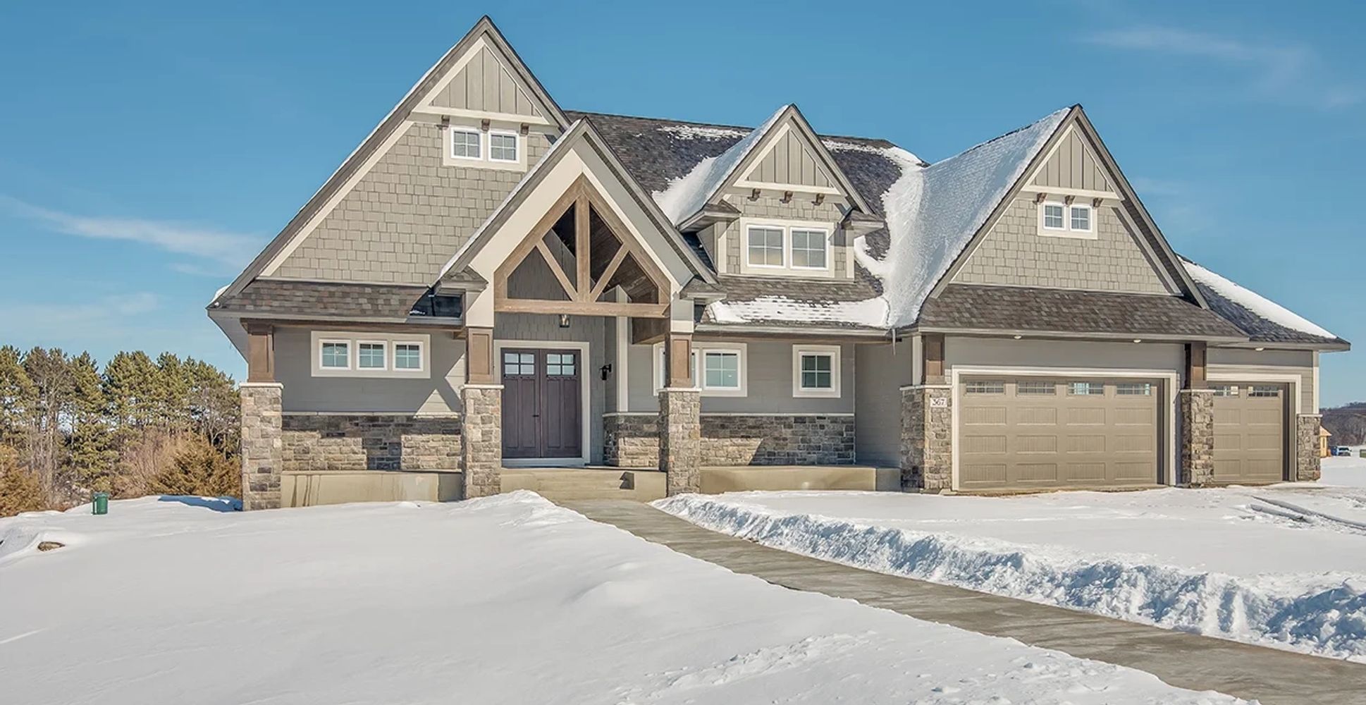 Modern house with snow-covered yard and clear blue sky.