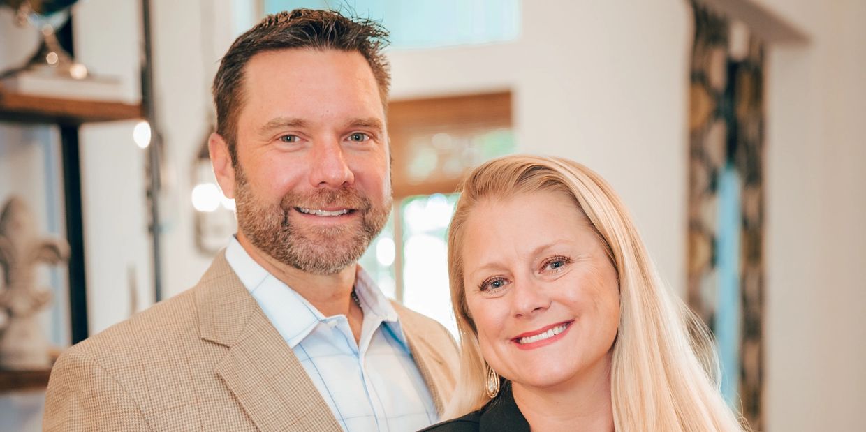 Smiling couple posing together indoors in a warmly lit room.