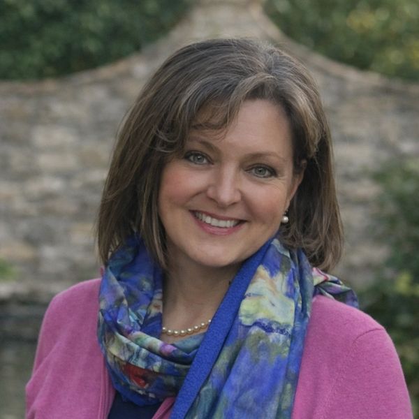Smiling woman wearing a colorful scarf and pink sweater.